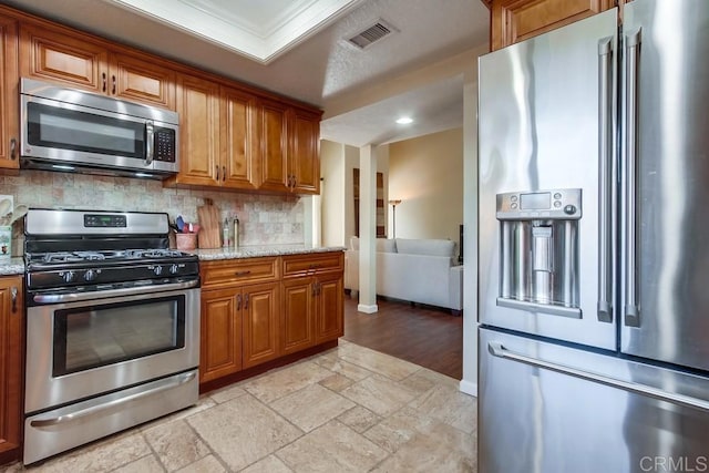 1023 Mimosa Ave, Vista, CA 92081 - kitchen with appliances with stainless steel finishes, brown cabinets, stone tile floors, backsplash, and crown molding