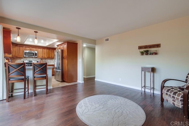 1023 Mimosa Ave, Vista, CA 92081 - kitchen featuring appliances with stainless steel finishes, wood finished floors, a peninsula, a tray ceiling, and brown cabinets