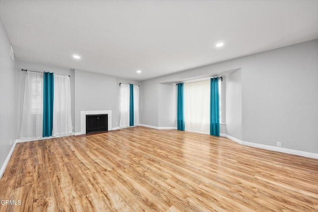 unfurnished living room featuring a fireplace, recessed lighting, wood finished floors, and baseboards