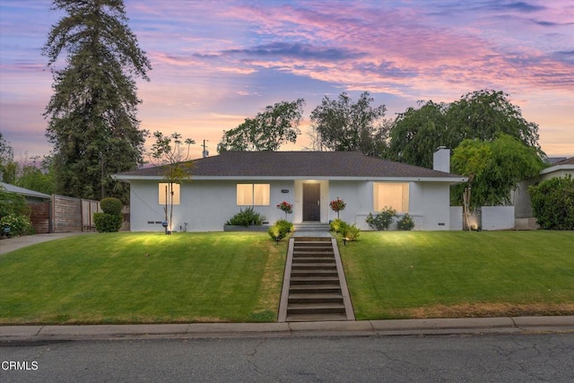 ranch-style home featuring a front lawn, a chimney, roof with shingles, stucco siding, and fence