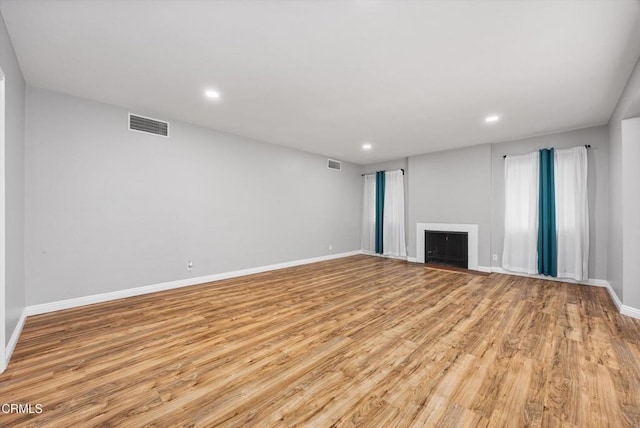 unfurnished living room featuring baseboards, visible vents, wood finished floors, and recessed lighting