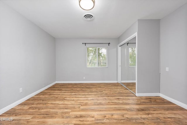 unfurnished bedroom with a closet, visible vents, light wood-style flooring, and baseboards
