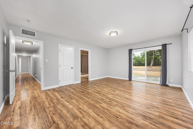 unfurnished room featuring visible vents, light wood finished floors, and baseboards
