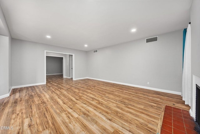 unfurnished living room with a fireplace, visible vents, wood finished floors, and baseboards