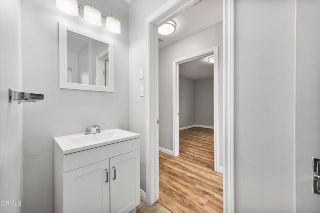 bathroom with wood finished floors, vanity, and baseboards