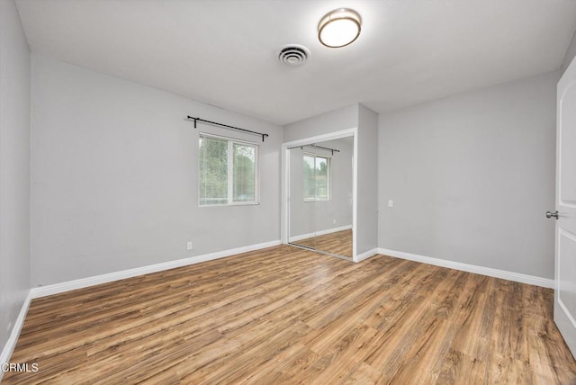 unfurnished bedroom featuring visible vents, light wood-type flooring, a closet, and baseboards