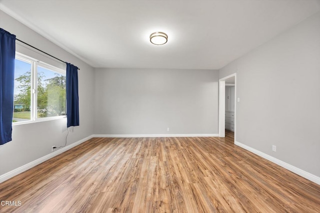 spare room featuring baseboards and light wood-style floors