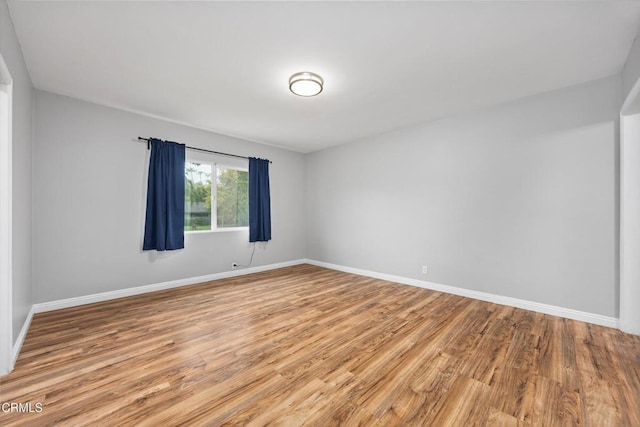 unfurnished room featuring baseboards and light wood-style flooring