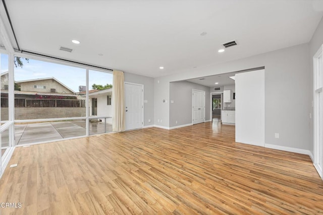 unfurnished living room with baseboards, visible vents, and light wood-style floors