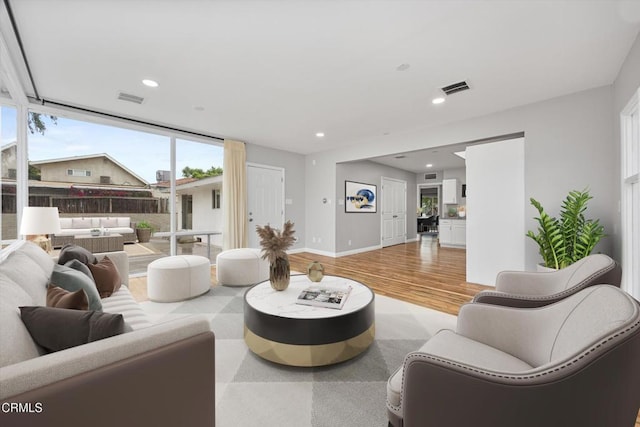living area with baseboards, visible vents, light wood-style flooring, and recessed lighting