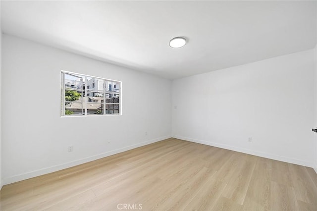 empty room with baseboards and light wood finished floors