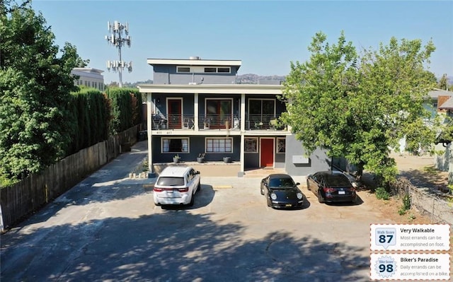 view of front of home featuring fence, a balcony, and uncovered parking