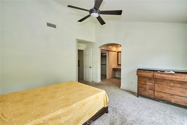 carpeted bedroom with a walk in closet, visible vents, arched walkways, baseboards, and high vaulted ceiling