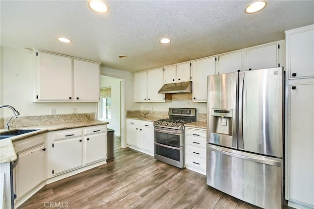 kitchen with appliances with stainless steel finishes, under cabinet range hood, recessed lighting, and a textured ceiling