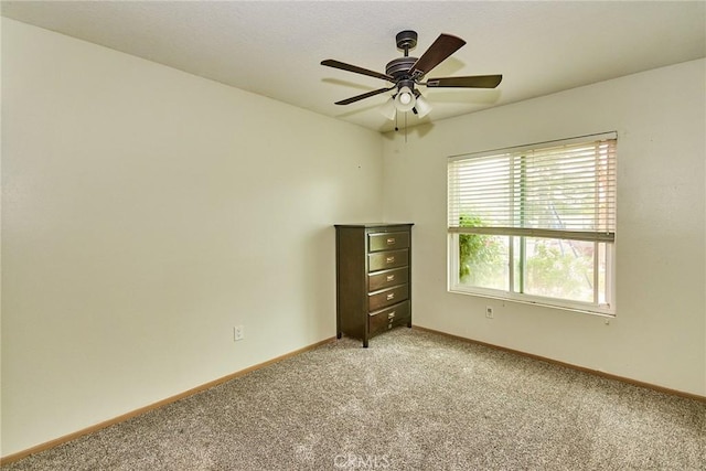 empty room with baseboards, ceiling fan, and light colored carpet
