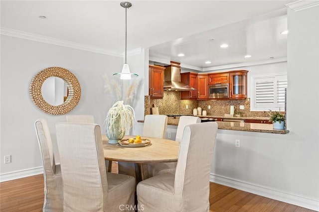 dining space featuring light wood-type flooring, recessed lighting, ornamental molding, and baseboards