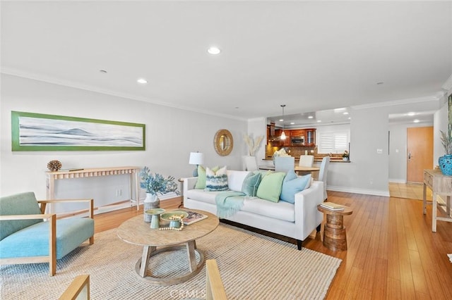 living area featuring baseboards, recessed lighting, crown molding, and light wood-style flooring