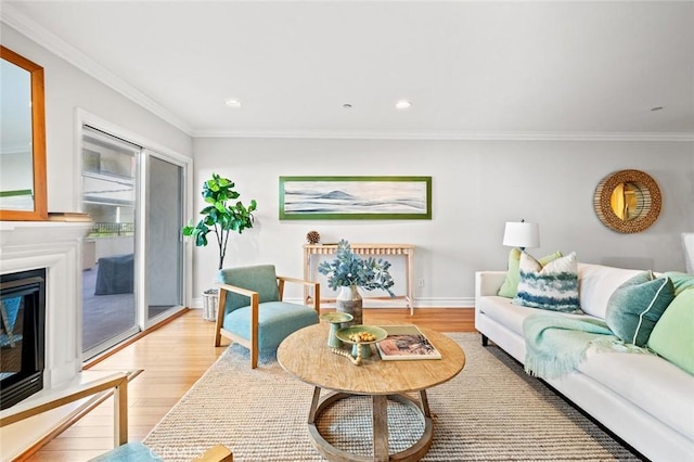 living room featuring crown molding, light wood finished floors, and a glass covered fireplace