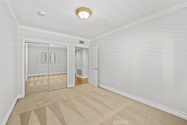 unfurnished bedroom with baseboards, visible vents, crown molding, and carpet