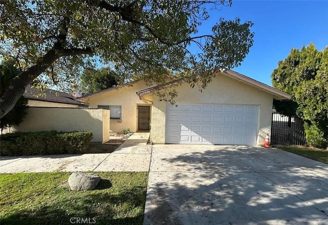 view of front of house with stucco siding, fence, driveway, and an attached garage