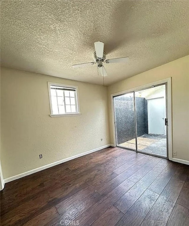 empty room with a textured ceiling, a ceiling fan, dark wood-style floors, and baseboards