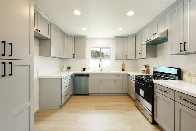 kitchen featuring gray cabinetry, appliances with stainless steel finishes, under cabinet range hood, and a sink