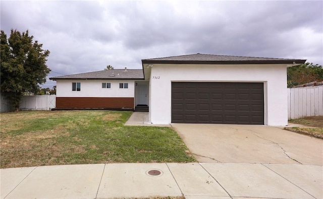 view of front facade featuring stucco siding, fence, driveway, and a front yard