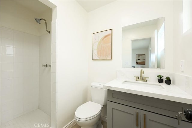 full bathroom featuring toilet, a tile shower, and vanity