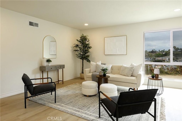 living room featuring baseboards, visible vents, wood finished floors, and recessed lighting