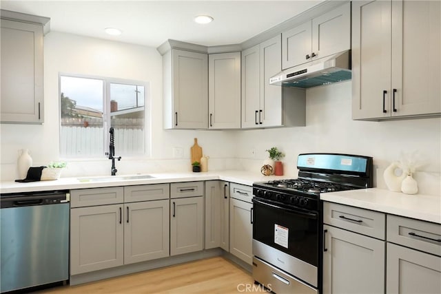 kitchen featuring a sink, under cabinet range hood, gray cabinets, light countertops, and appliances with stainless steel finishes