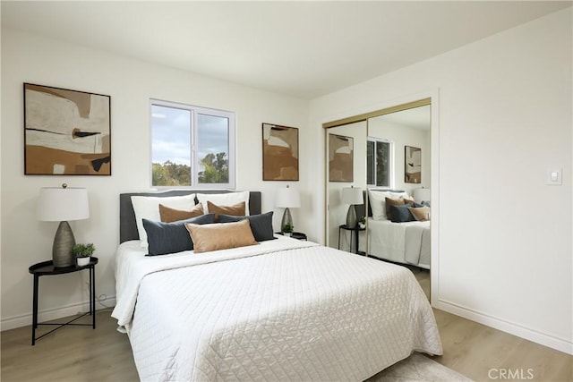 bedroom featuring baseboards, a closet, and light wood-style flooring