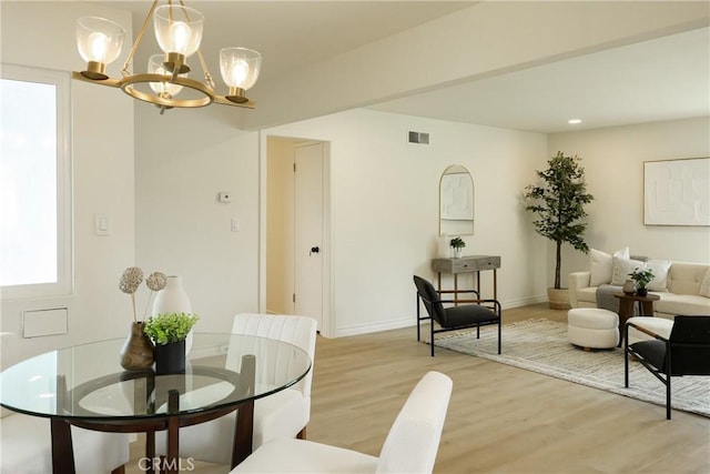 dining area featuring visible vents, a notable chandelier, baseboards, and light wood-style floors