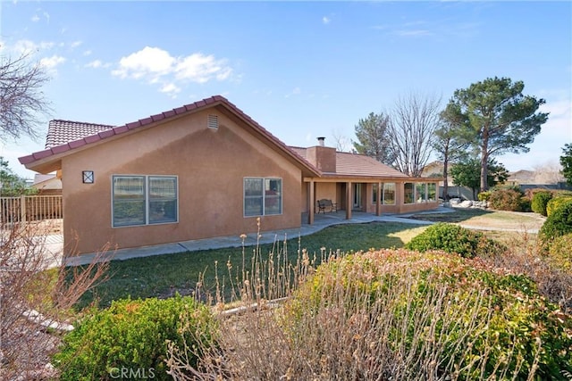 back of property featuring stucco siding, a lawn, and a patio