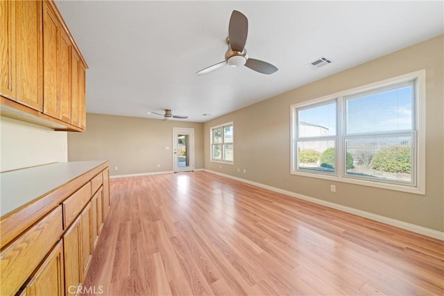 unfurnished living room featuring a ceiling fan, visible vents, light wood-style flooring, and baseboards