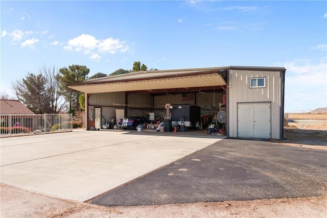 garage with driveway, a carport, and fence