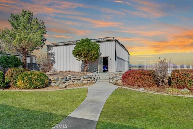 mid-century inspired home with a lawn, fence, a pole building, and an outbuilding