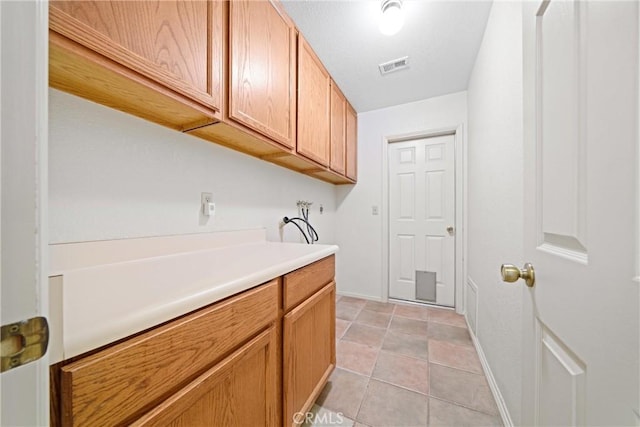 laundry area featuring hookup for a washing machine, light tile patterned floors, cabinet space, baseboards, and visible vents