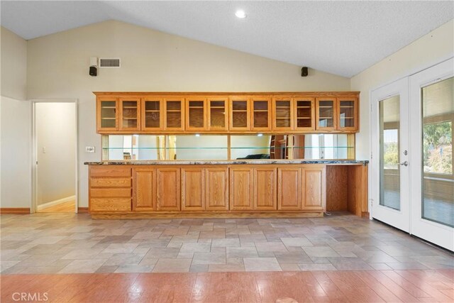 kitchen featuring visible vents, glass insert cabinets, french doors, and high vaulted ceiling