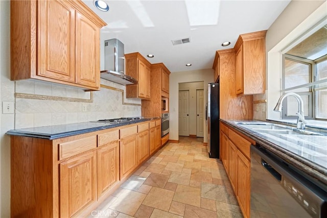 kitchen with stainless steel appliances, wall chimney range hood, dark countertops, a sink, and visible vents