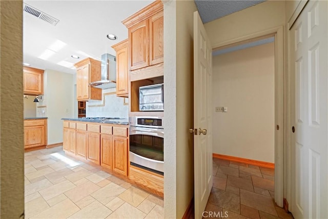 kitchen with recessed lighting, light brown cabinets, stone tile flooring, oven, and visible vents