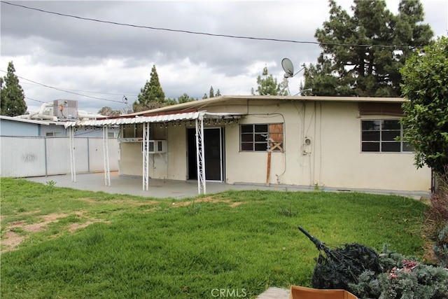 rear view of property featuring a lawn, fence, a patio area, and stucco siding
