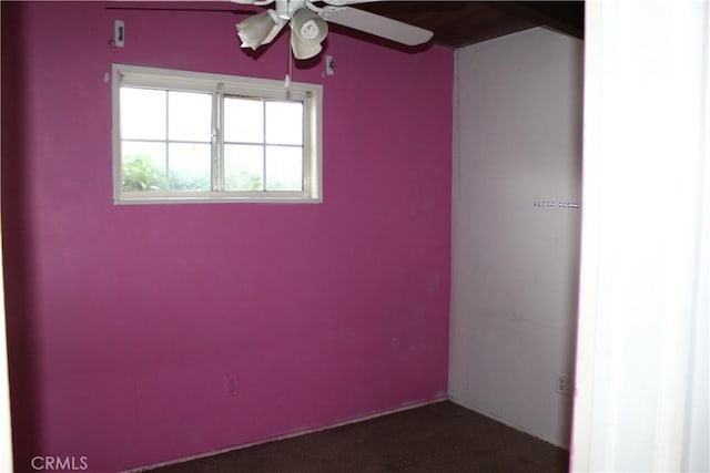 spare room with a ceiling fan and dark carpet