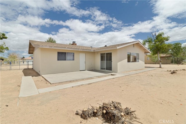 rear view of house with a patio, a chimney, stucco siding, and fence