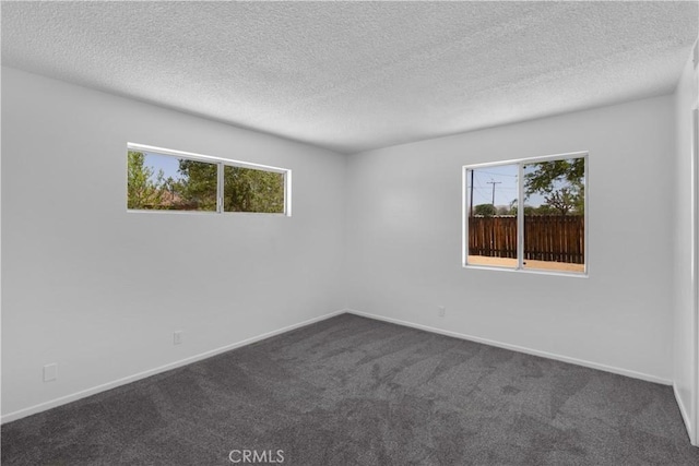 unfurnished room featuring baseboards, dark carpet, and a textured ceiling