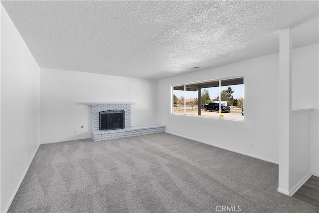 unfurnished living room with a textured ceiling, carpet, and a brick fireplace