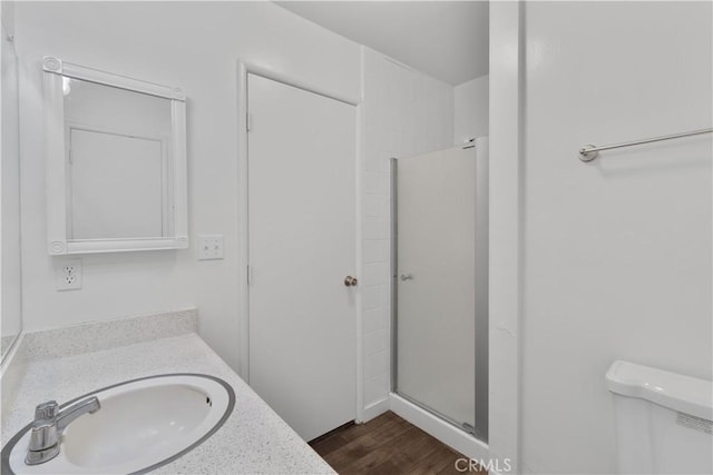bathroom with wood finished floors, a shower stall, toilet, and vanity