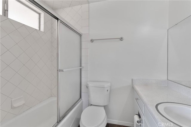 bathroom with enclosed tub / shower combo, baseboards, toilet, and vanity