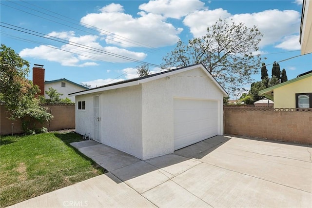 detached garage with fence and concrete driveway