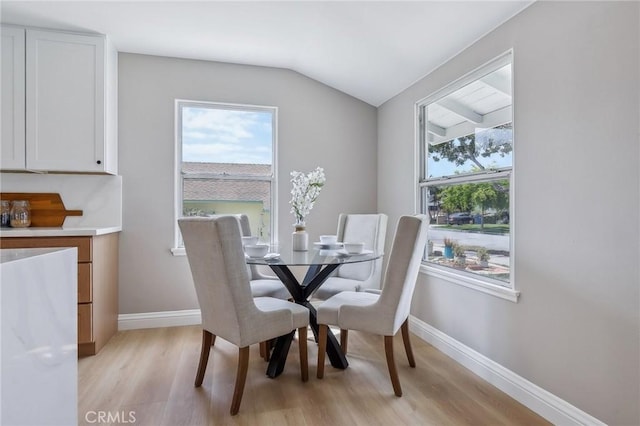dining area with light wood-style floors, baseboards, plenty of natural light, and lofted ceiling