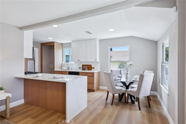 kitchen with light countertops, vaulted ceiling, a sink, and light wood-style flooring